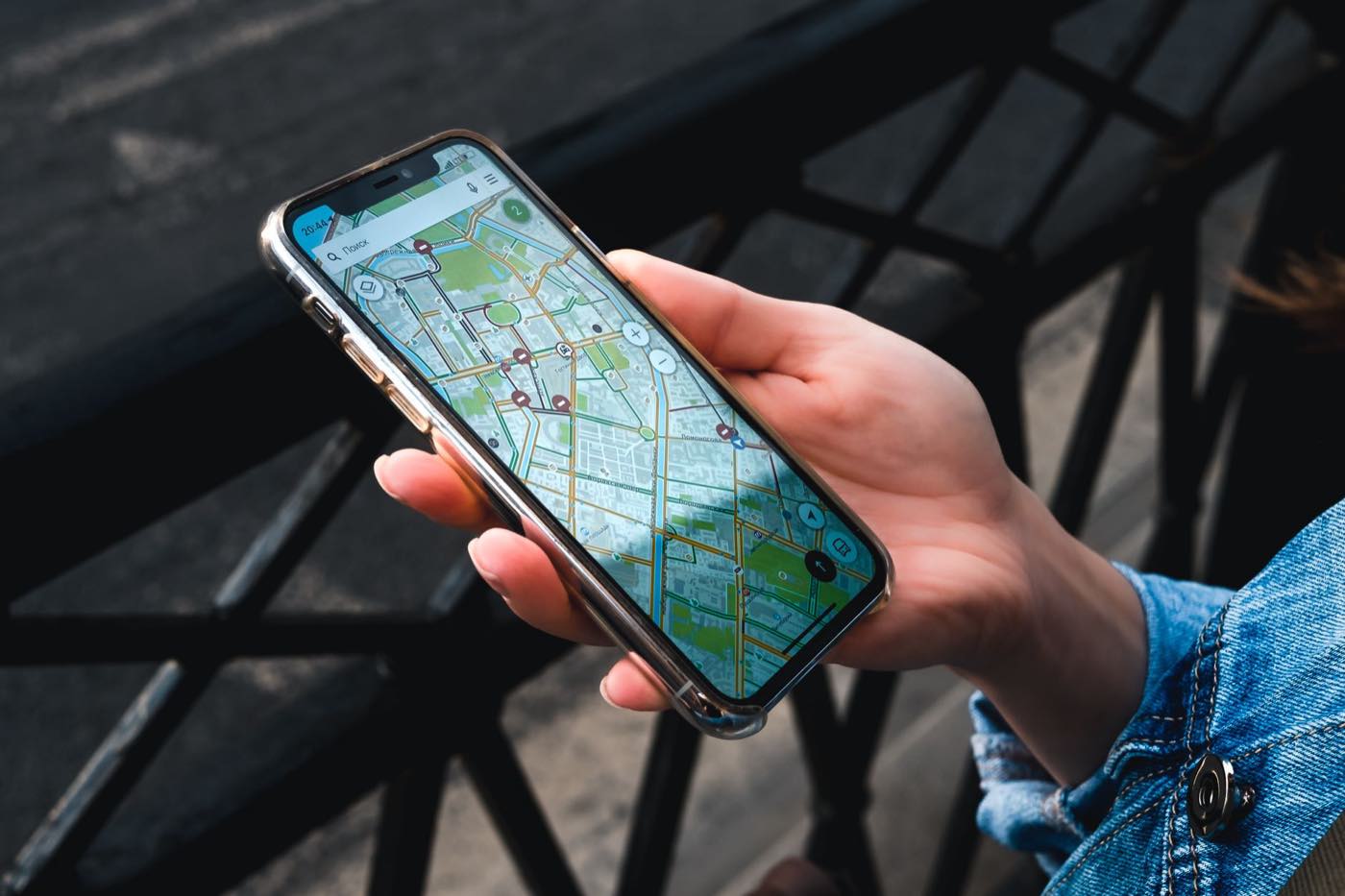 Main tenant un smartphone qui affiche une application de carte, en extérieur